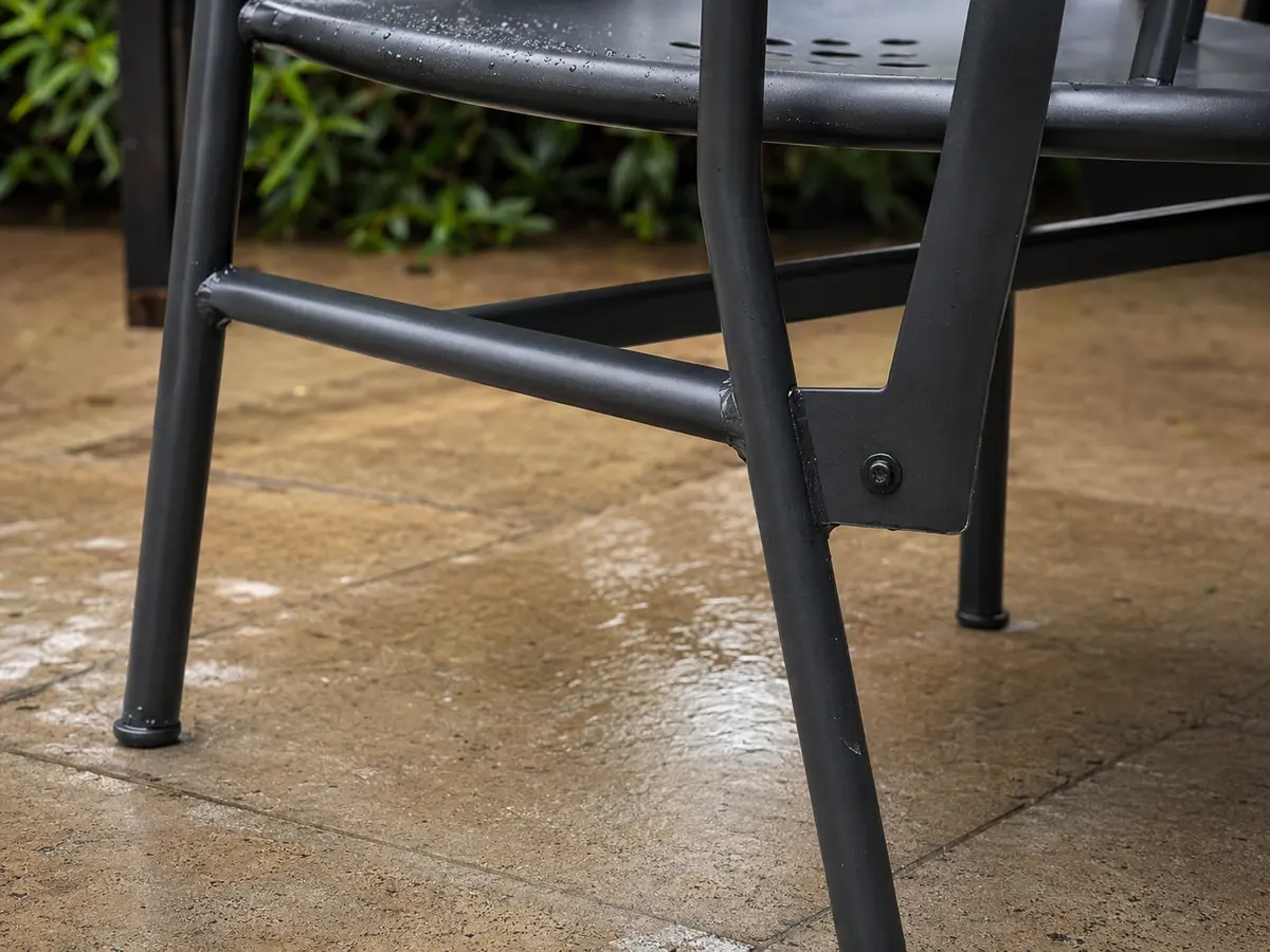 Wet metal chair frame showing welds, fastener, bracing, glides, and wear points to inspect
