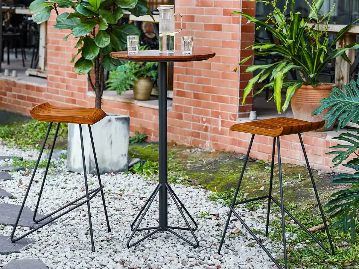 YZ-OBT01 round bar table arranged with two high stools on an outdoor café patio