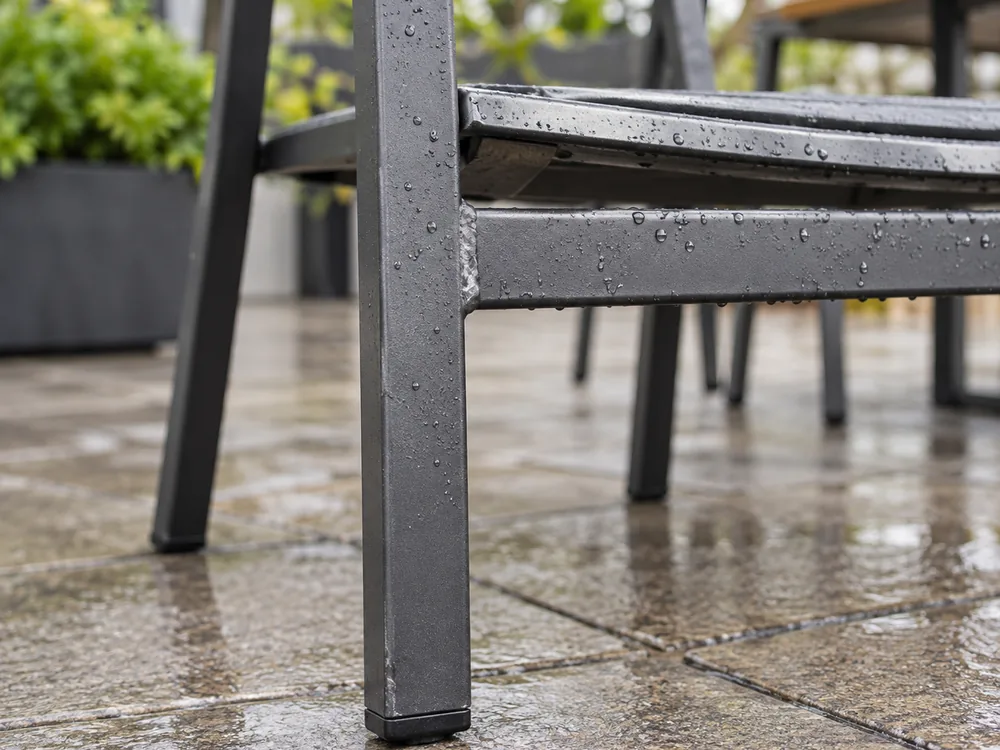 El mejor mobiliario de exterior para proyectos de restauración comercial Gotas de agua de lluvia alrededor de la unión y del punto de contacto con el suelo de una silla genérica de exterior de metal con recubrimiento en polvo